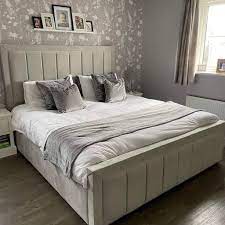 Furnish UK bumper panel line bed frame in beige with upholstered headboard and footboard in a cozy bedroom