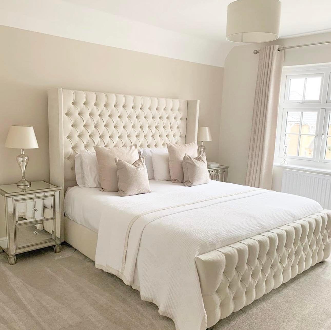 Cream chesterfield wingback bed with tufted headboard and footboard in a bright bedroom by Furnish UK