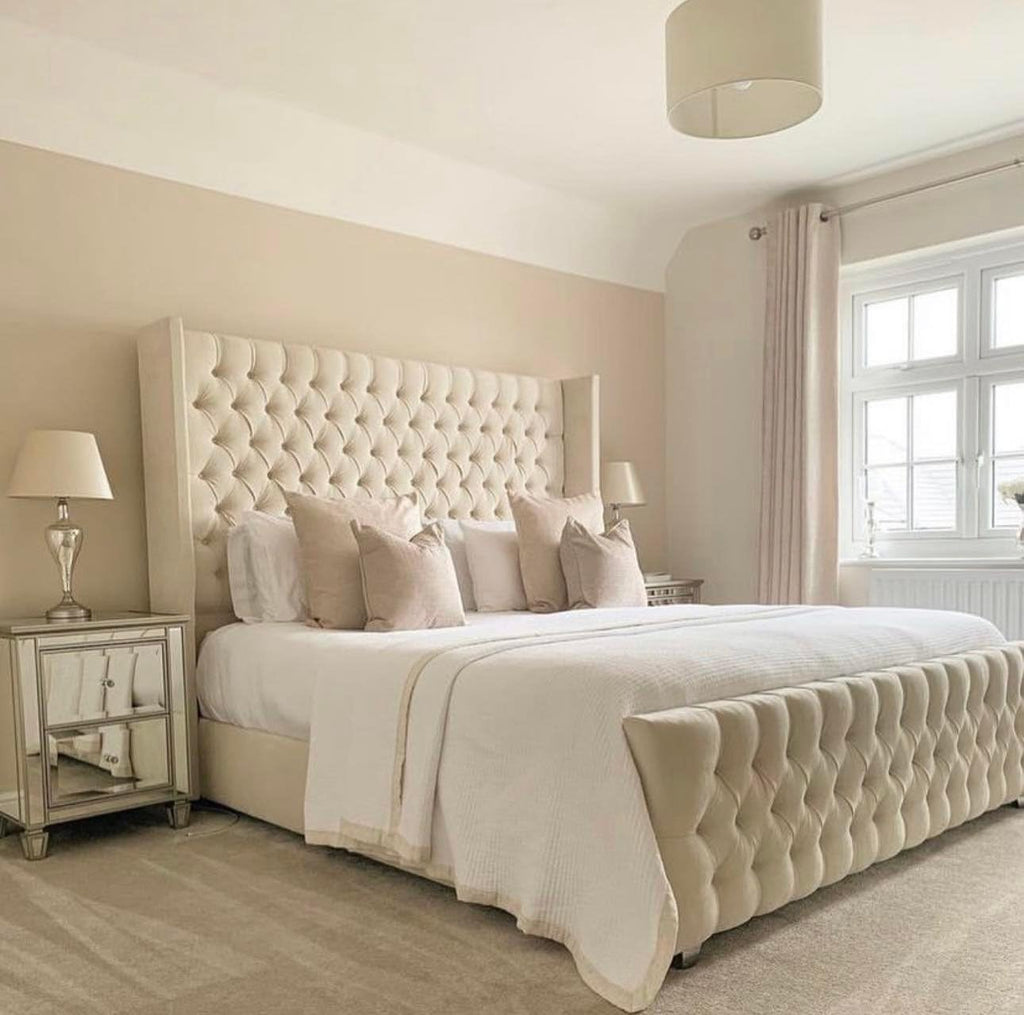 Elegant beige chesterfield wingback bed with tufted headboard and footboard in a cozy bedroom