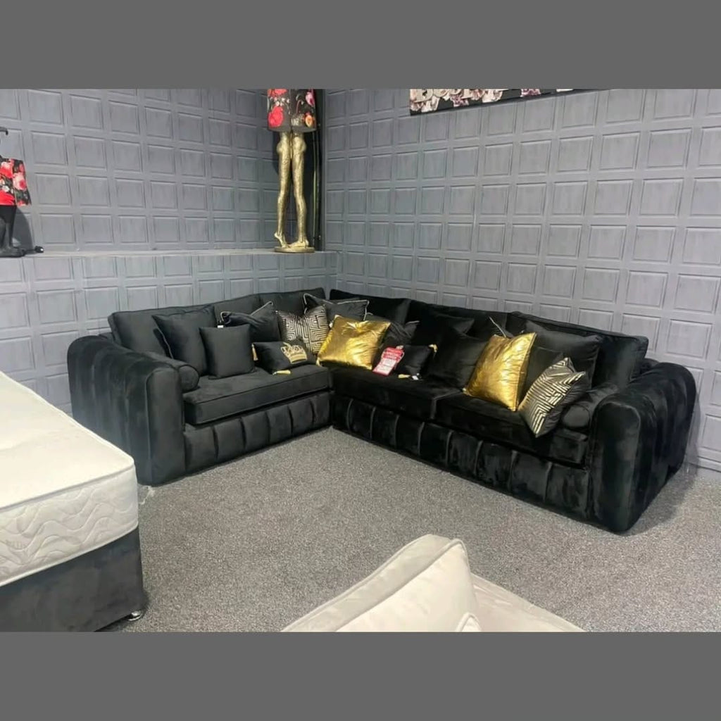 Furnish UK modern L-shaped sofa in black velvet corner sofa with decorative gold and patterned pillows