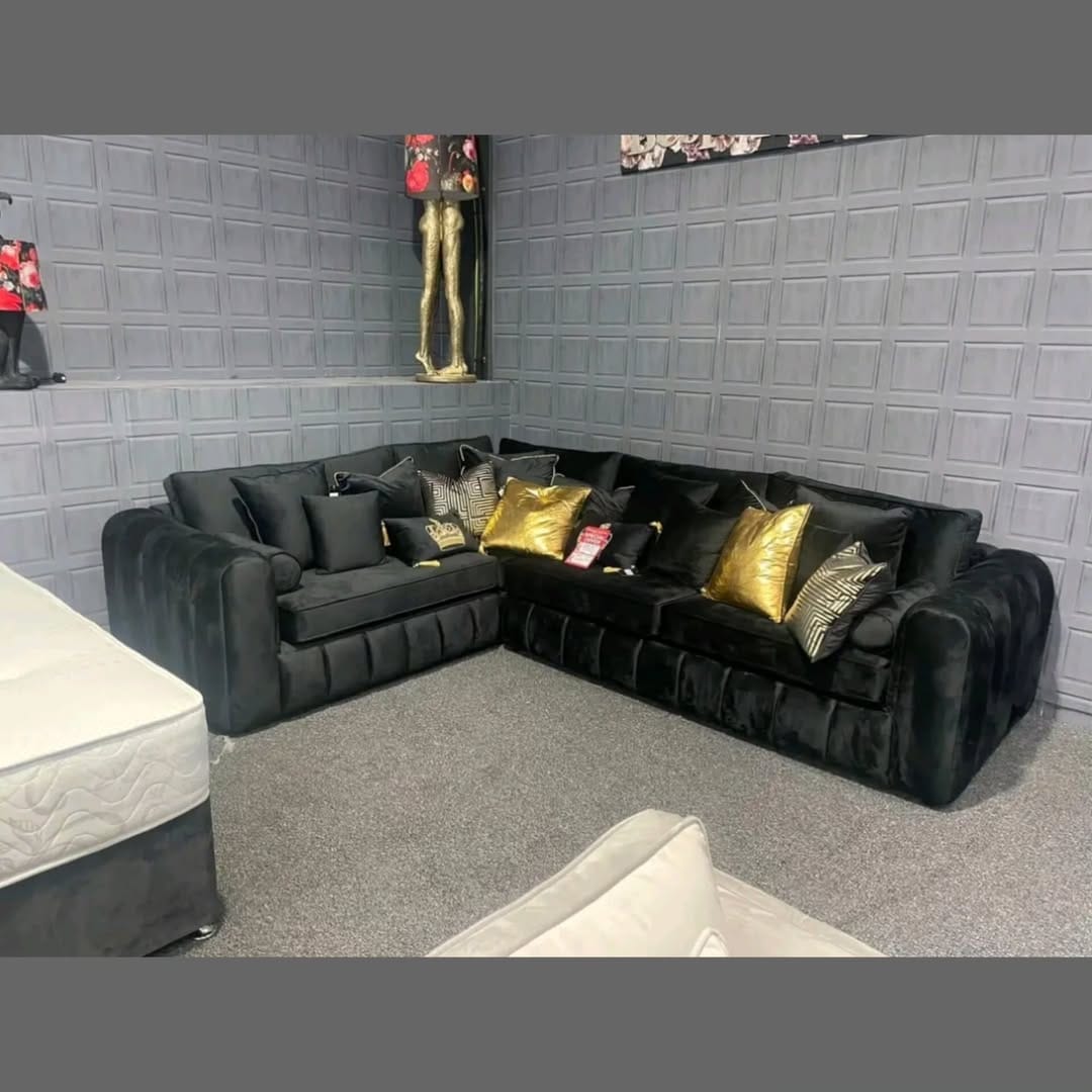 Furnish UK modern L-shaped sofa in black velvet corner sofa with decorative gold and patterned pillows