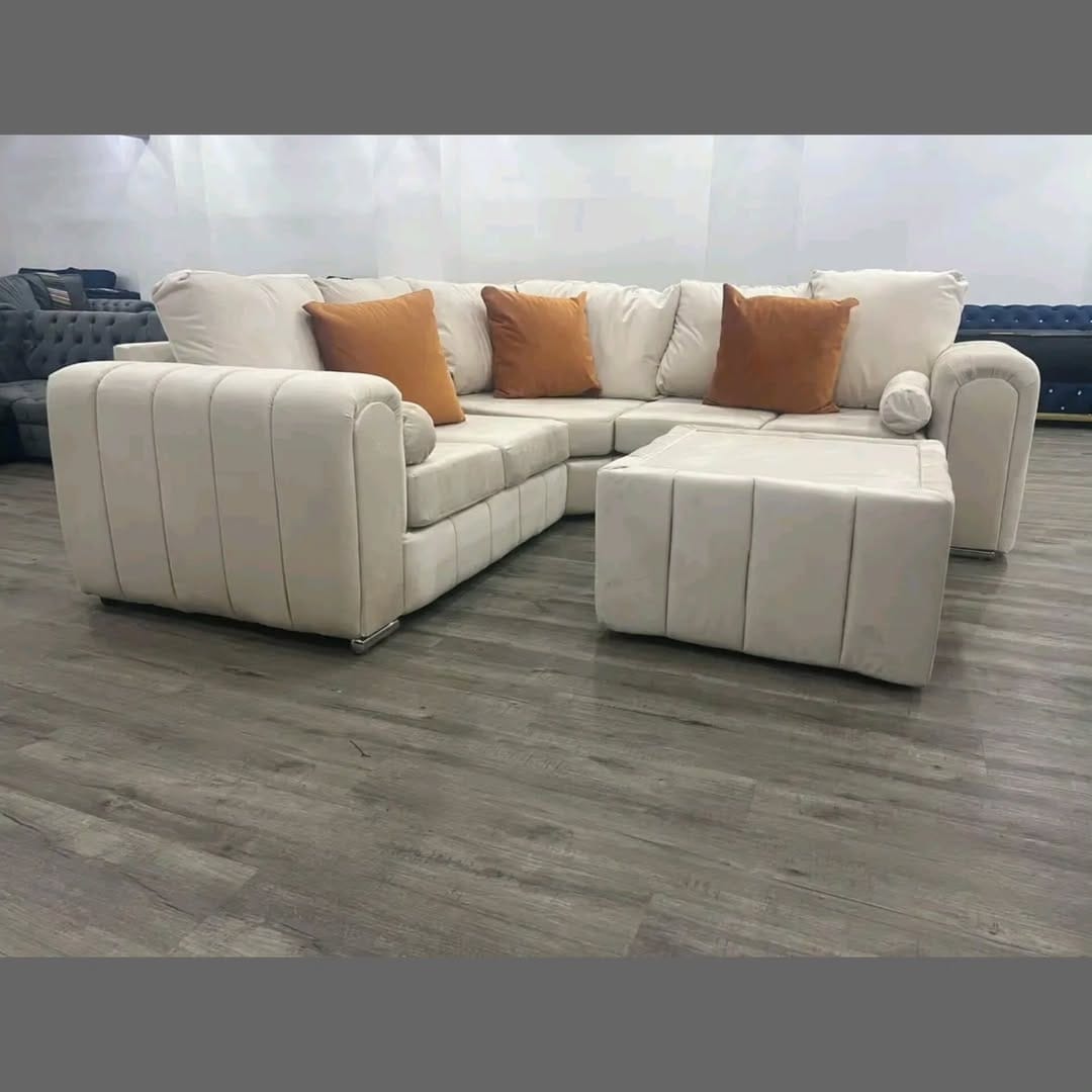 Furnish UK modern L-shaped sofa in cream with brown accent pillows and matching ottoman on wood floor