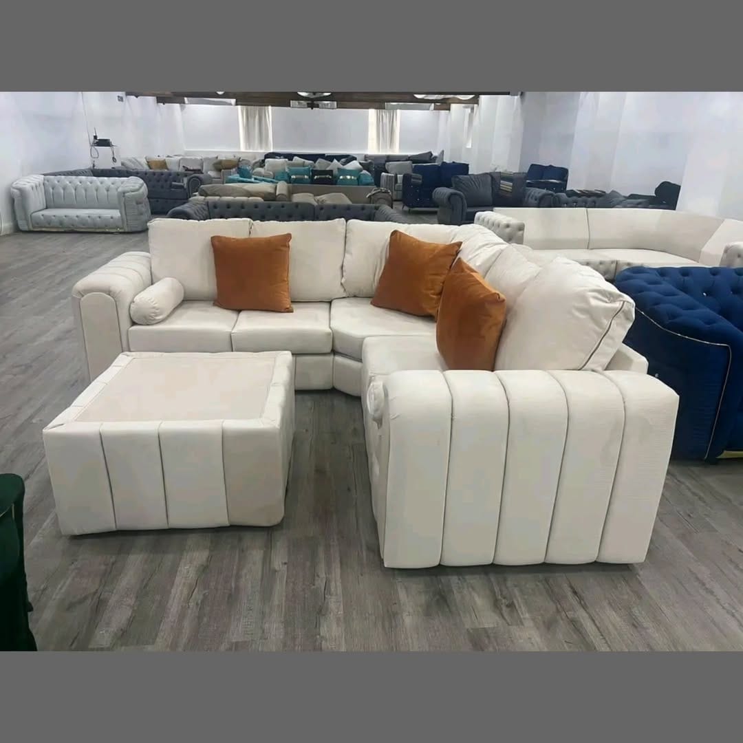 Furnish UK modern L-shaped sofa in white with orange cushions and matching ottoman on wooden floor