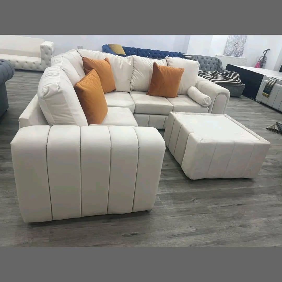Furnish UK modern L-shaped sofa in white with orange cushions and matching ottoman on gray floor