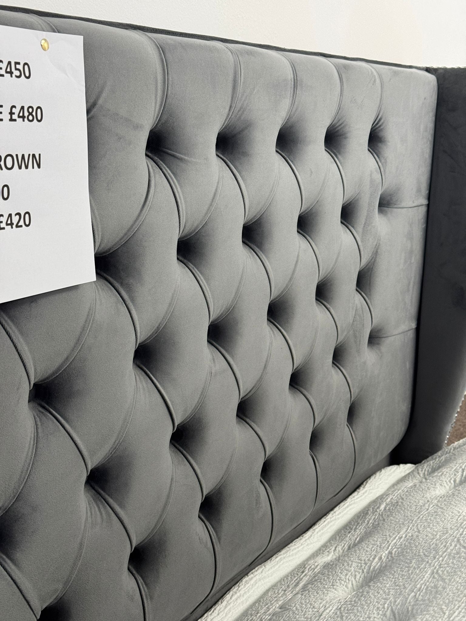 Gray tufted headboard of an ottoman divan bed with storage by Furnish UK