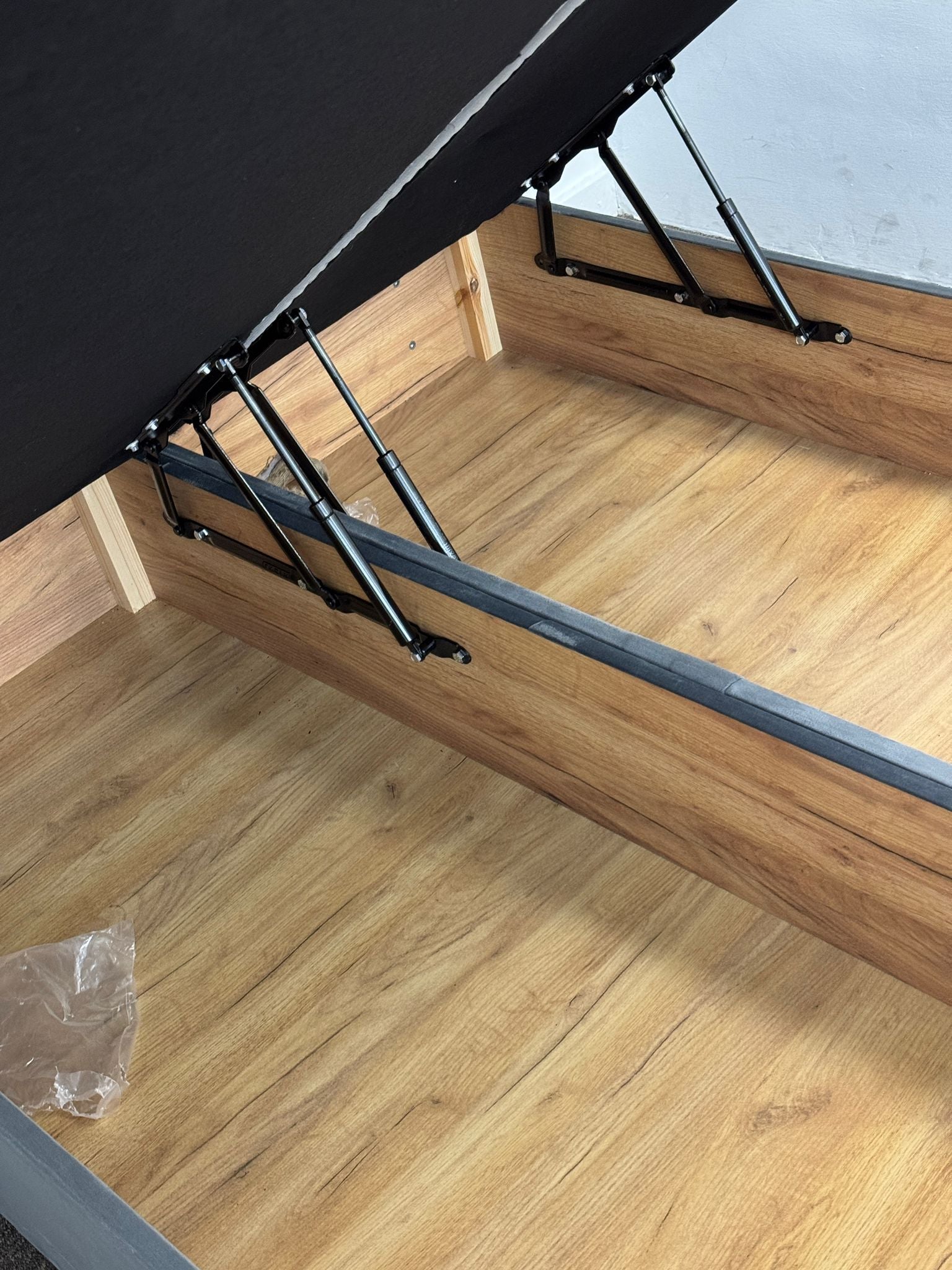 Close-up of wooden frame and metal hinges inside ottoman divan bed with storage by Furnish UK