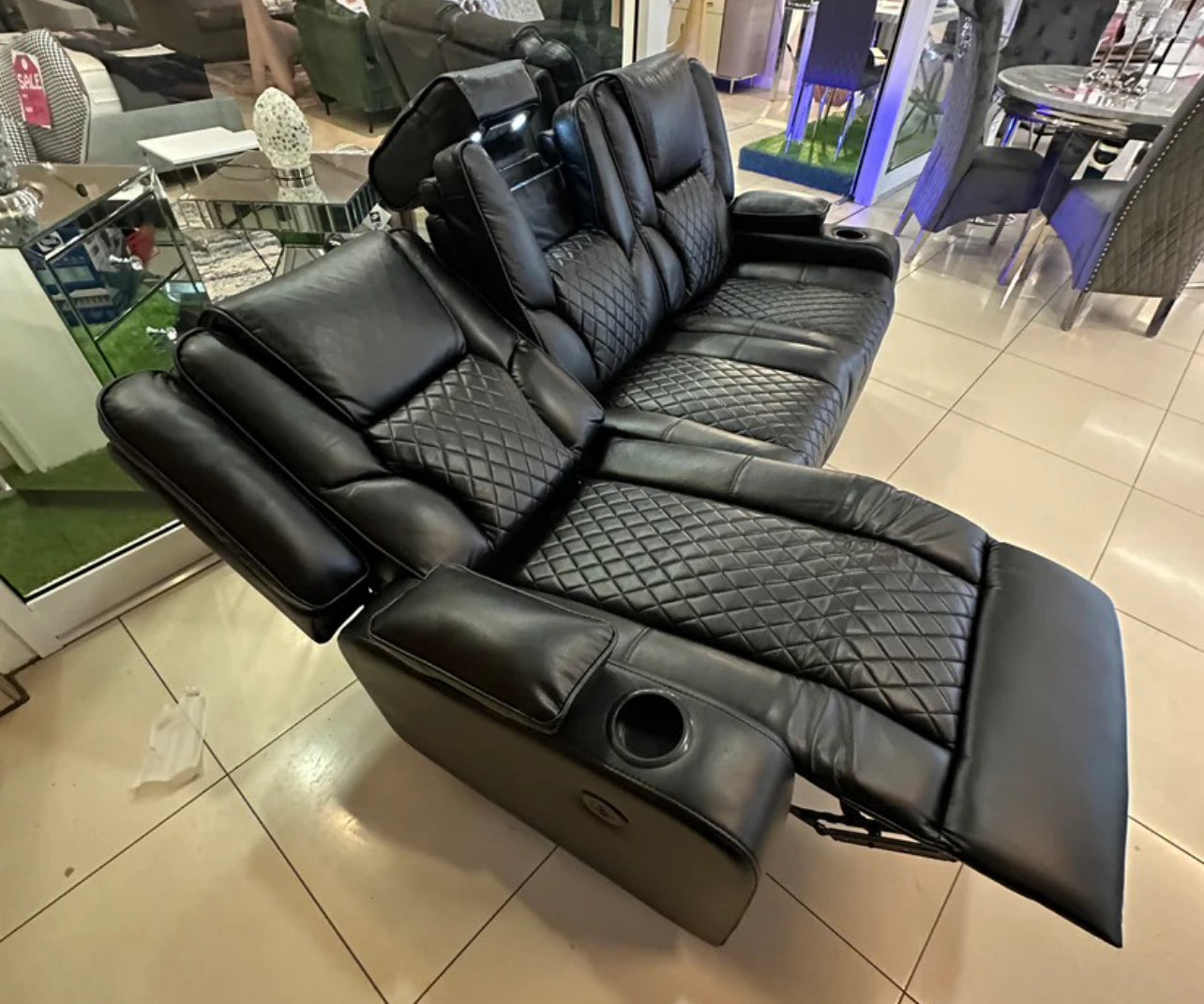 Furnish UK black electric leather recliner sofa with quilted seats and cup holders in a showroom