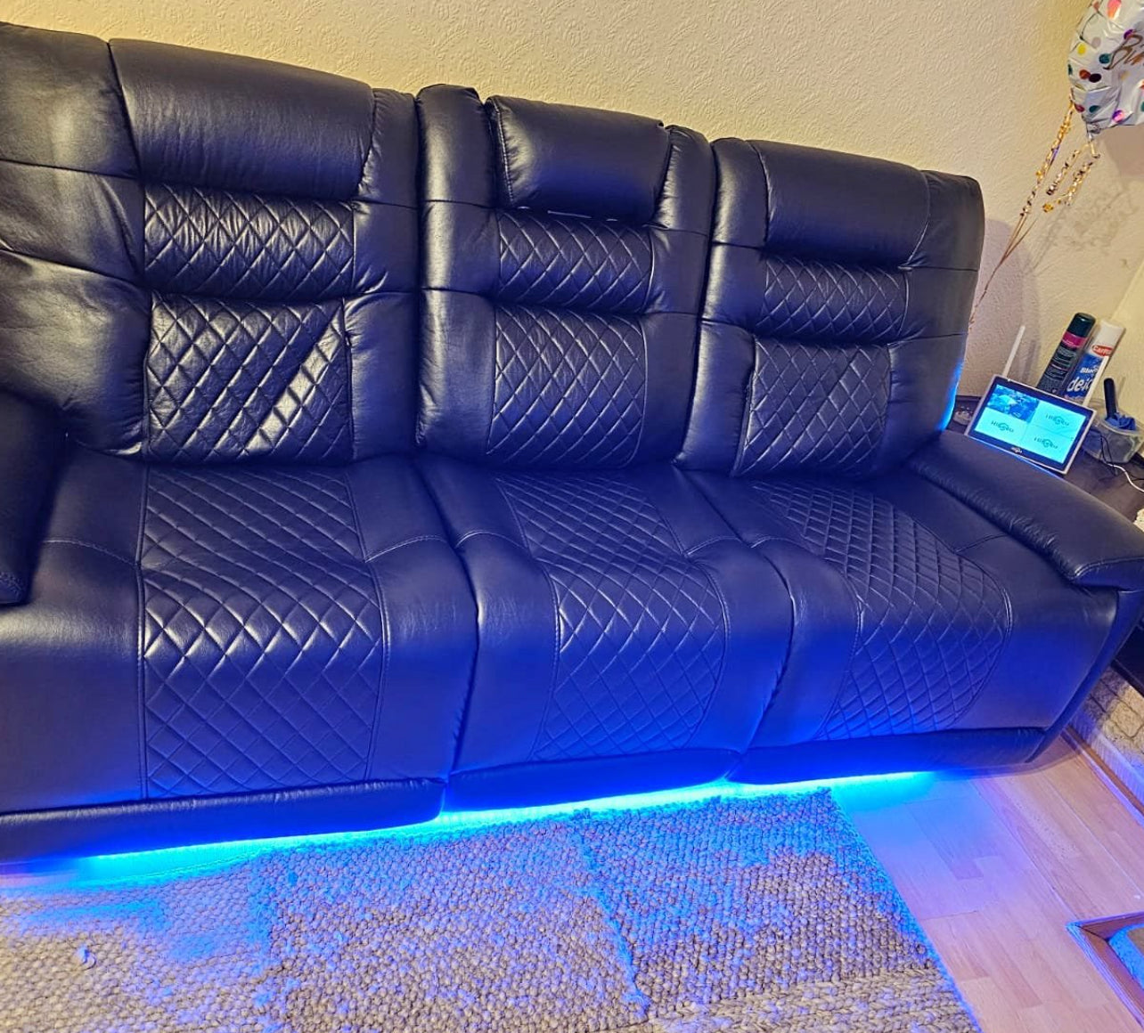 Black electric leather recliner sofa with quilted upholstery and blue LED lighting underneath