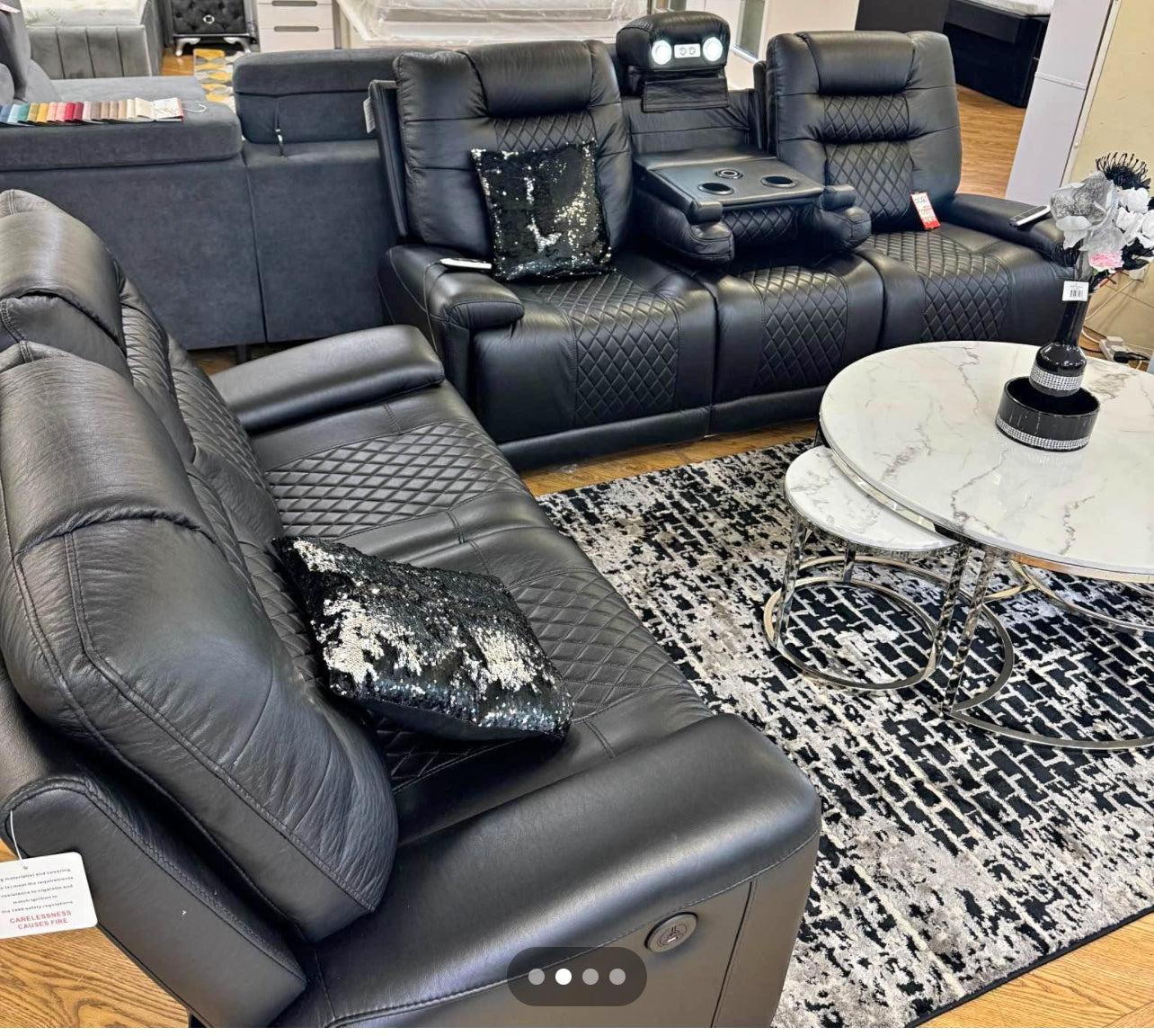 Black electric leather recliner sofa set with quilted design and cup holder console in modern living room