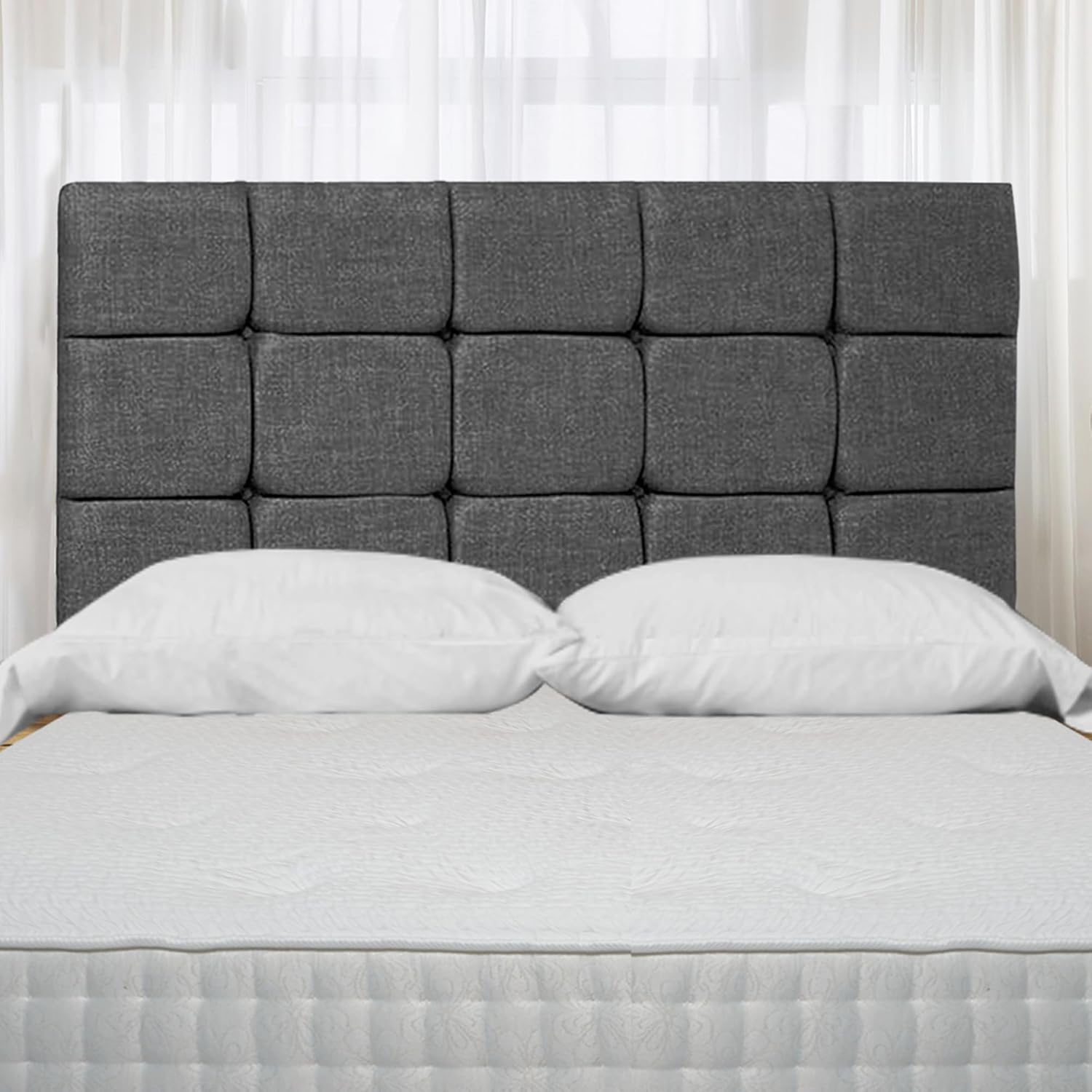 Modern upholstered divan bed with dark gray padded headboard and white mattress pillows