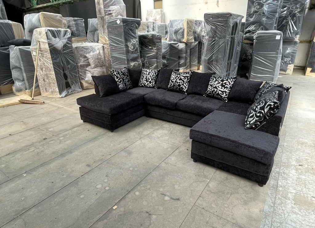 Furnish UK U shape fabric sofa with cushions in black color with patterned throw pillows in a warehouse