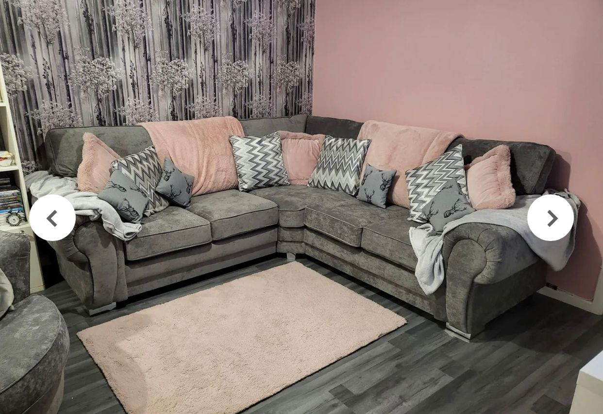 Verona corner sofa in dark gray with multiple patterned cushions and soft pink throws in a cozy living room